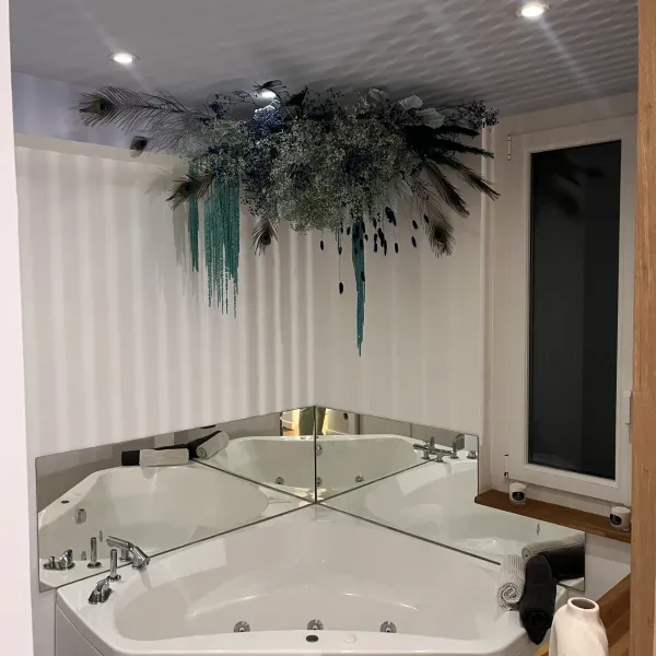 Suspension de fleurs séchées bleutées et de plumes de paon au-dessus d'un bain à remous