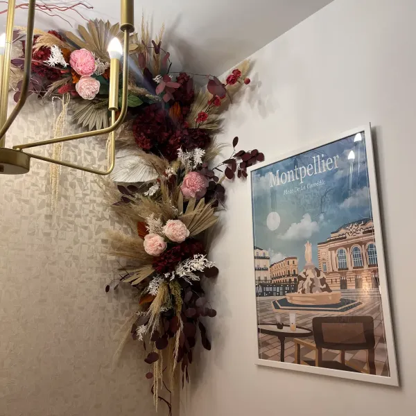 Détail d'une arche murale de fleurs séchées, tons bordeaux, rose poudré et pampa