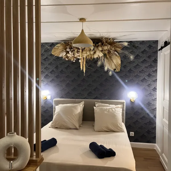 Composition de fleurs séchées dorées autour d'un luminaire, dans une chambre aux murs bleu nuit